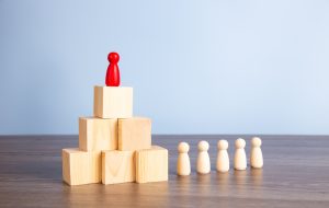 Wooden people figures on top of wooden blocks. Career growth, development and leadership